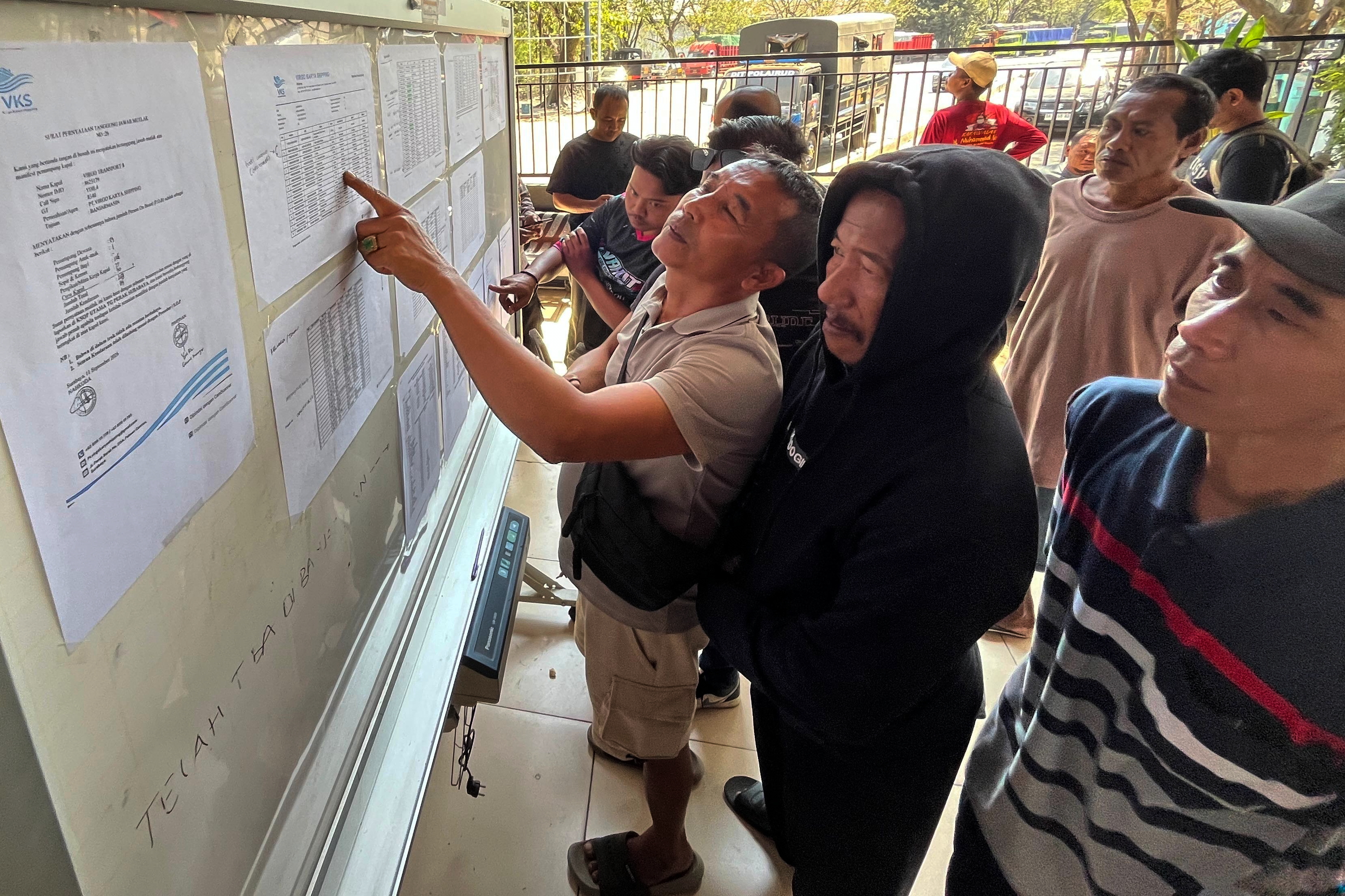 People check the passenger manifest of Virgo Transport 8 passenger ferry which overturned in bad weather in the Java Sea, at the rescuers